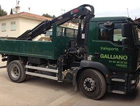 Camion de transport Galliano vert avec grue, stationné à l'extérieur.