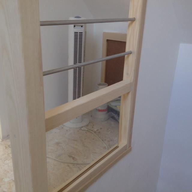Miroir de salle de bain reflétant une rampe en bois et un grand ventilateur colonne blanc dans une petite pièce