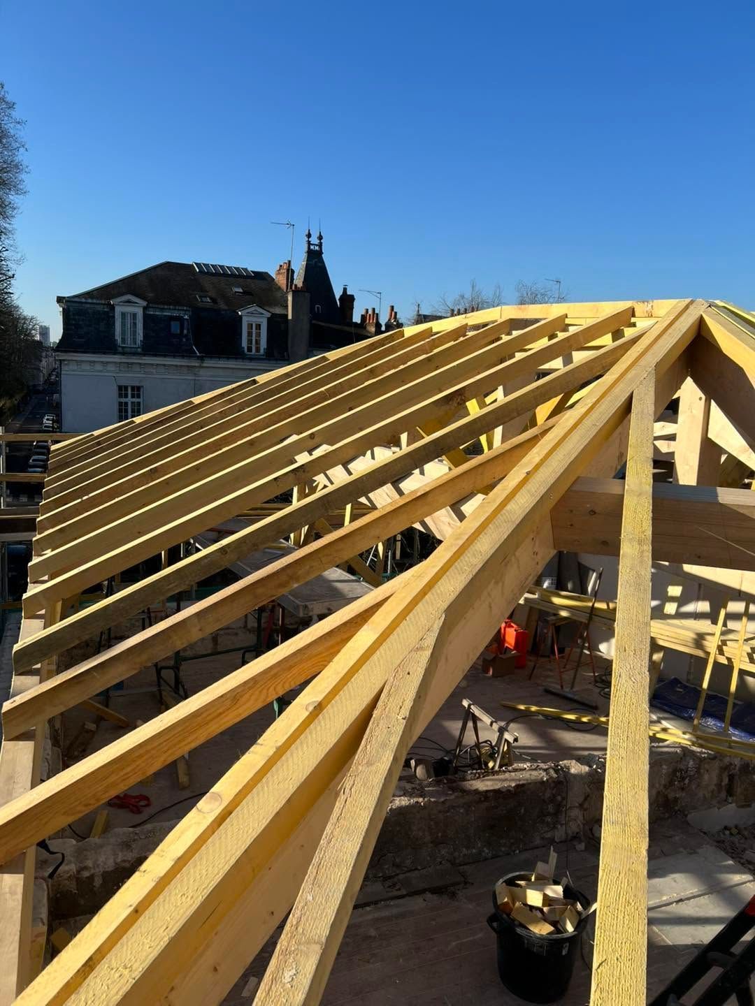 Charpente en bois en construction sur une maison en plein jour.