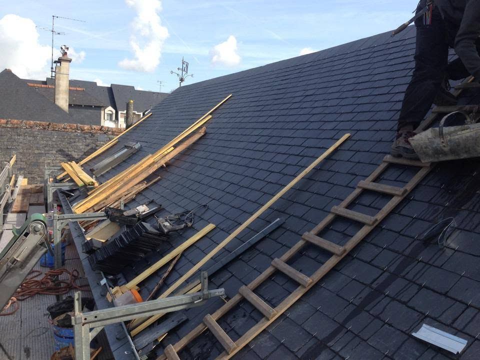 Toiture en réparation avec échelles et planches de bois sur bardeaux gris foncé.