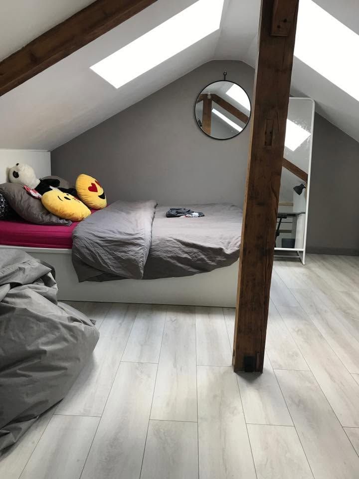 Chambre en mezzanine avec plafond mansardé, lit simple, peluches et poutre apparente.