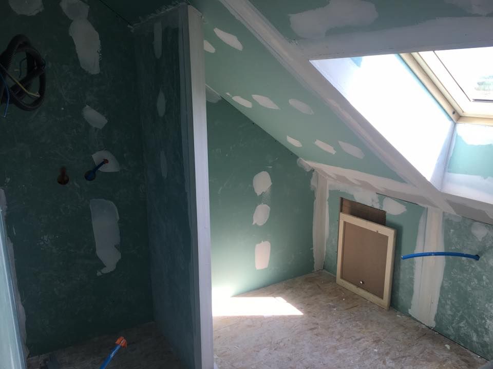 Petite pièce mansardée en rénovation avec murs verts, puits de lumière et réparations de cloisons sèches.