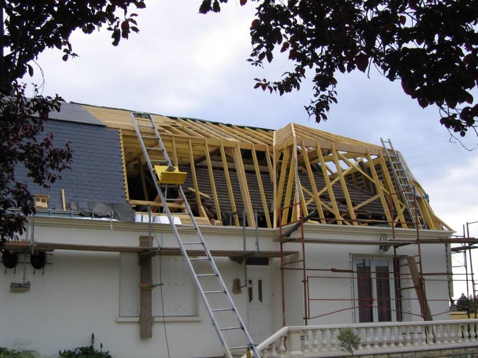 Toiture de maison en construction avec charpente en bois, échelle et échafaudage.