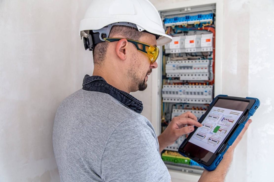Electricista trabajando y revisando en una instalación eléctrica.