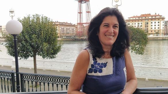 Una mujer con un vestido azul está parada frente a un cuerpo de agua.