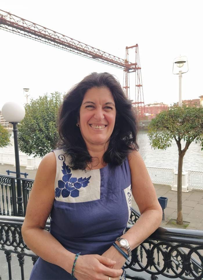 Una mujer está parada junto a una barandilla frente a un puente.