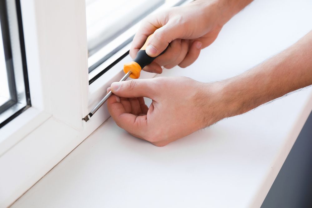 Una persona está arreglando una ventana con un destornillador.