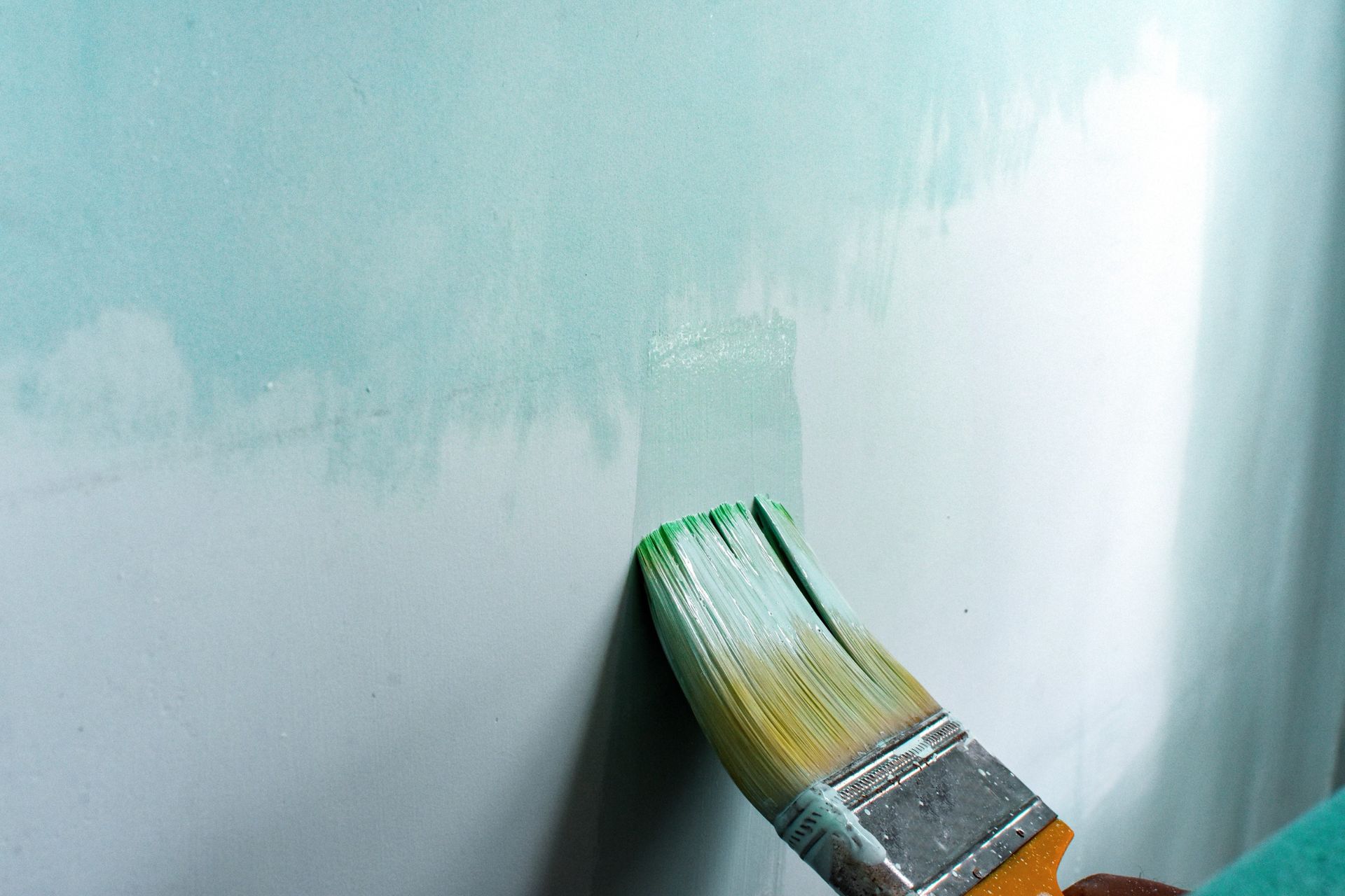 Una persona está pintando una pared con un pincel.