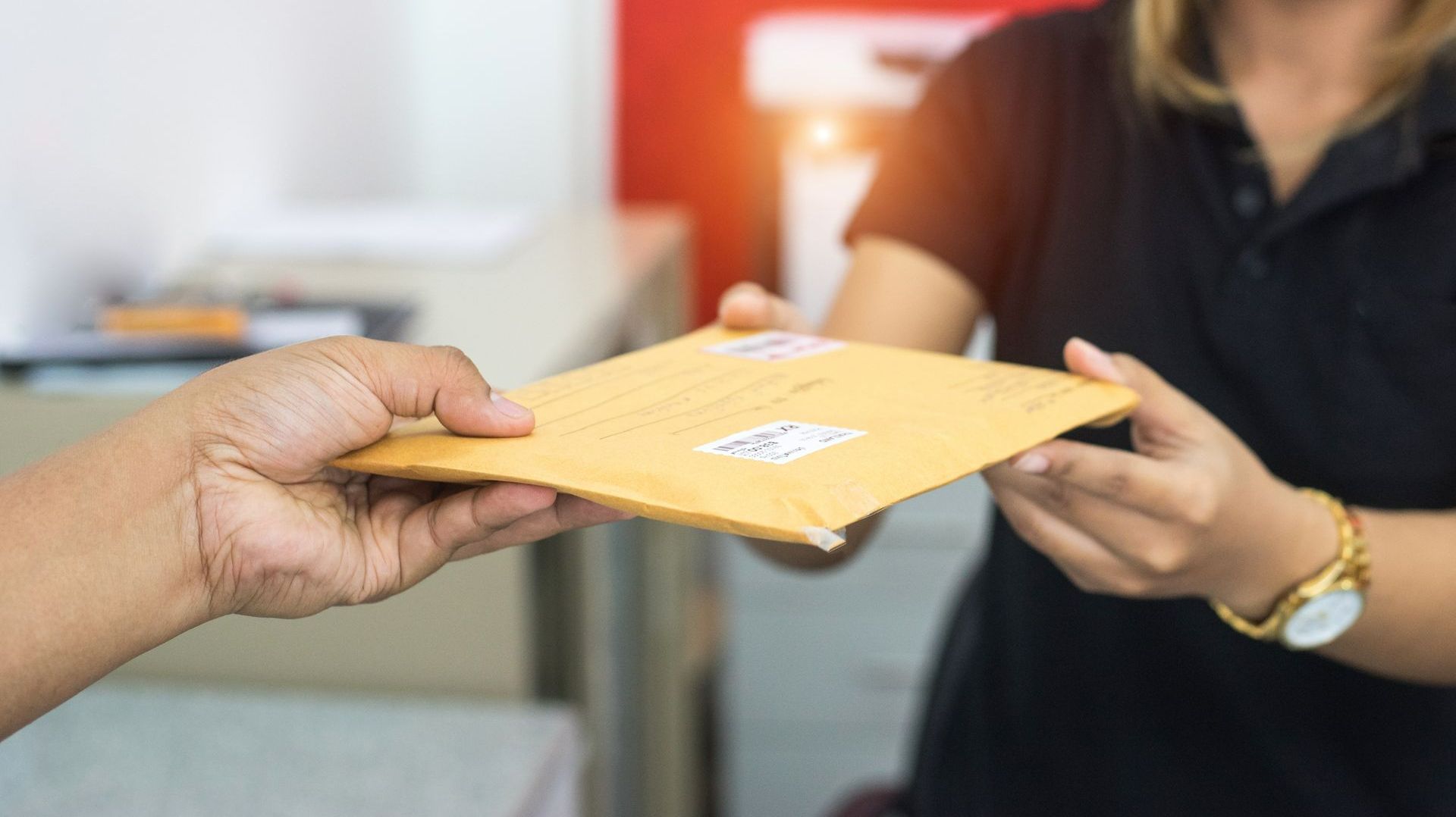Une personne qui tend l'enveloppe à une autre personne.
