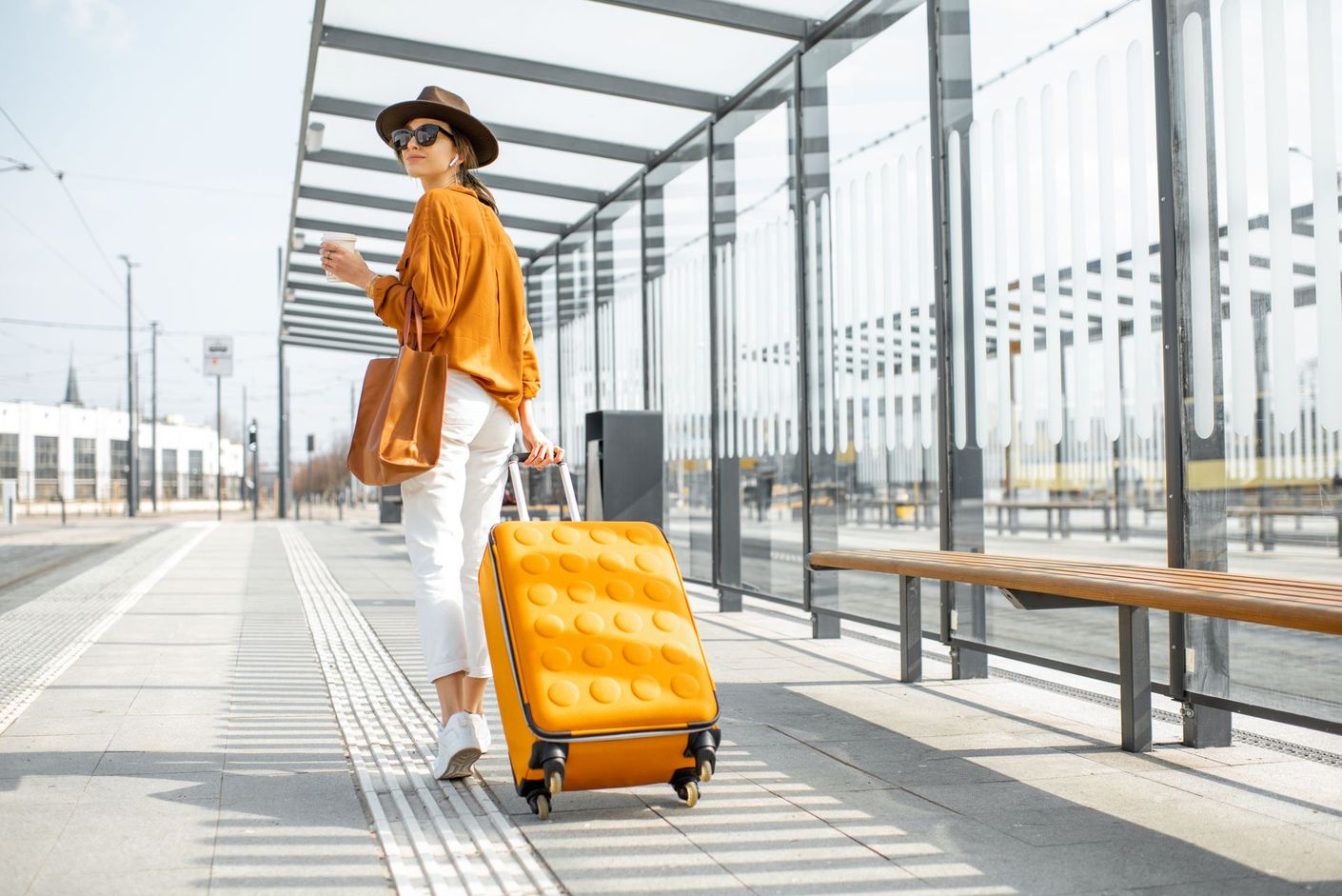 Une jeune femme qui marche avec une valise jaune.