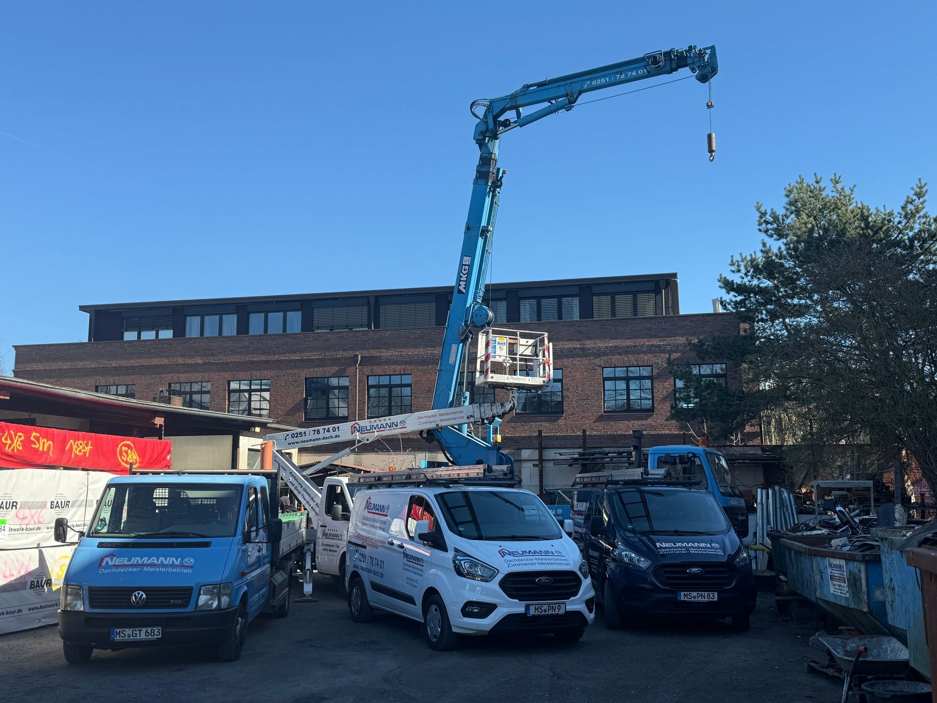 Eine Gruppe Lieferwagen parkt vor einem Gebäude, im Hintergrund ist ein Kran zu sehen.