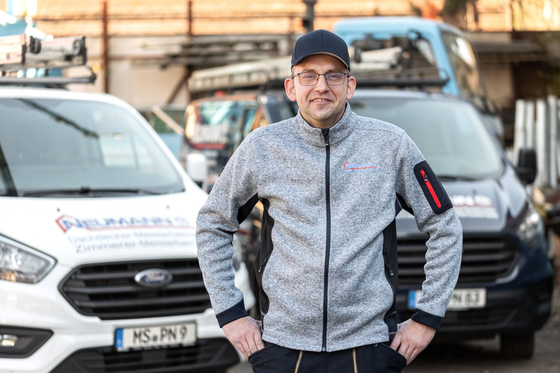 Ein Mann steht vor einer Reihe von Lieferwagen.