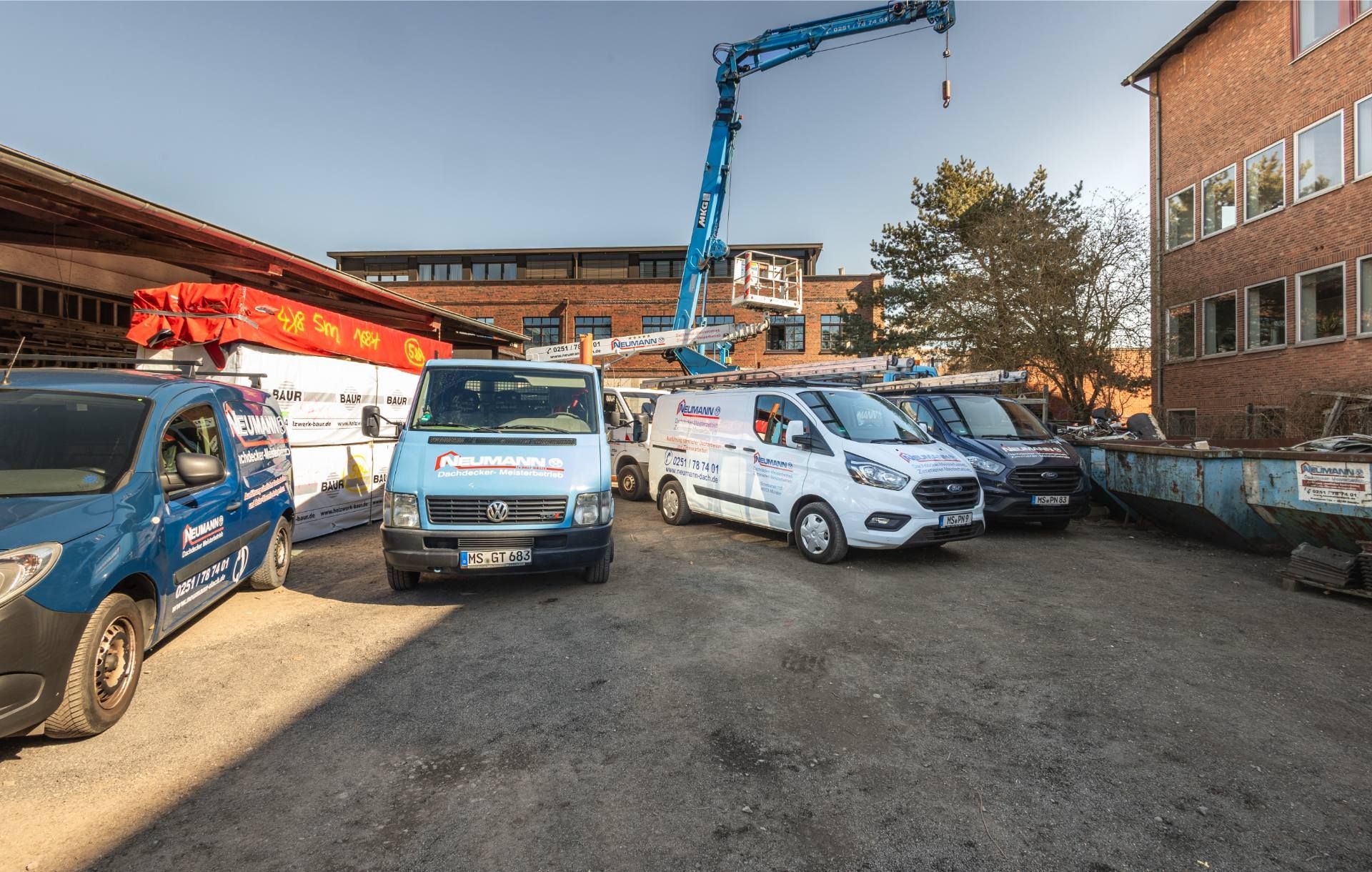 Auf einem Parkplatz vor einem Gebäude steht eine Reihe Lieferwagen.