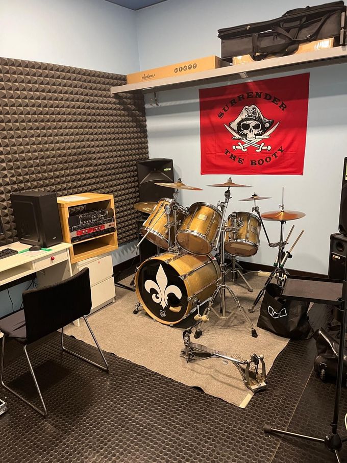 Batería con el logo de los Saints en un estudio de grabación, con bandera roja e insonorización.