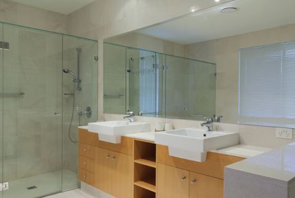 Un baño con dos lavabos, una ducha y un gran espejo.
