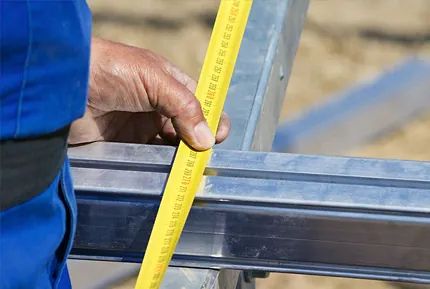 Una persona está midiendo un trozo de metal con una cinta métrica.