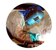 Un hombre que lleva una máscara de soldador está soldando una pieza de metal.