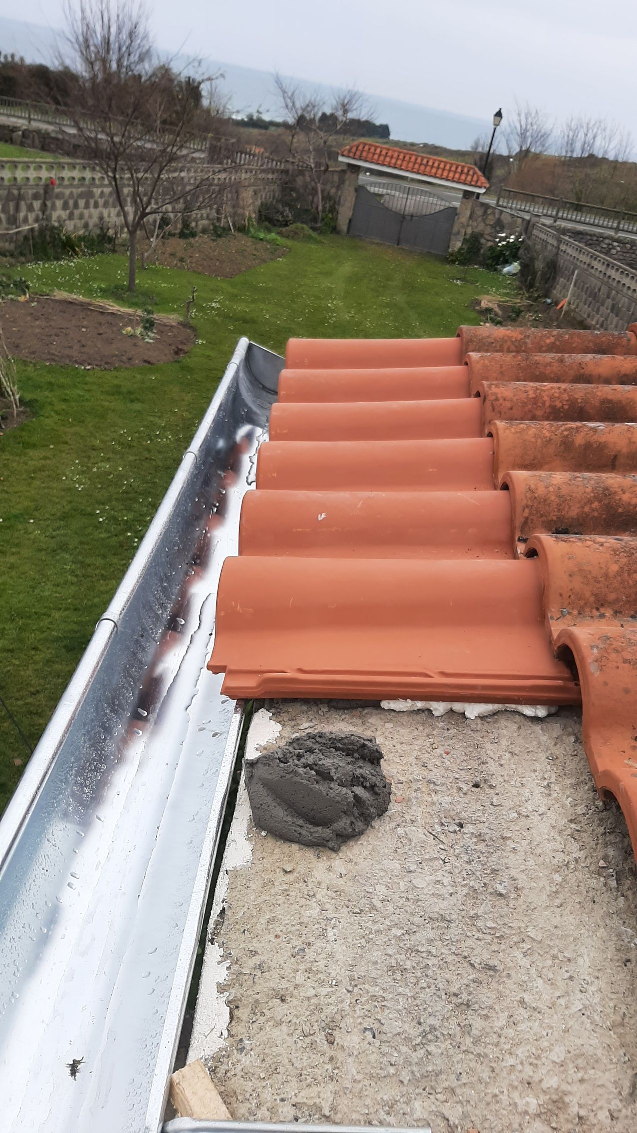 Un techo con tejas rojas y un canalón sobre él.