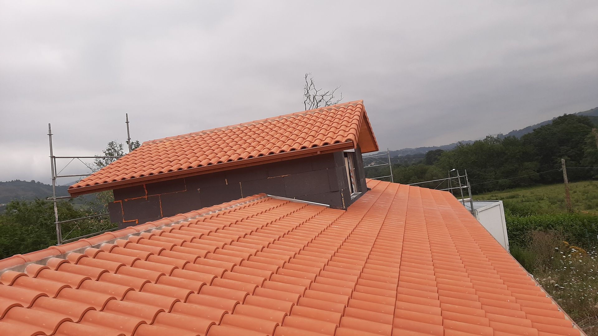 Un techo de tejas con una chimenea encima.