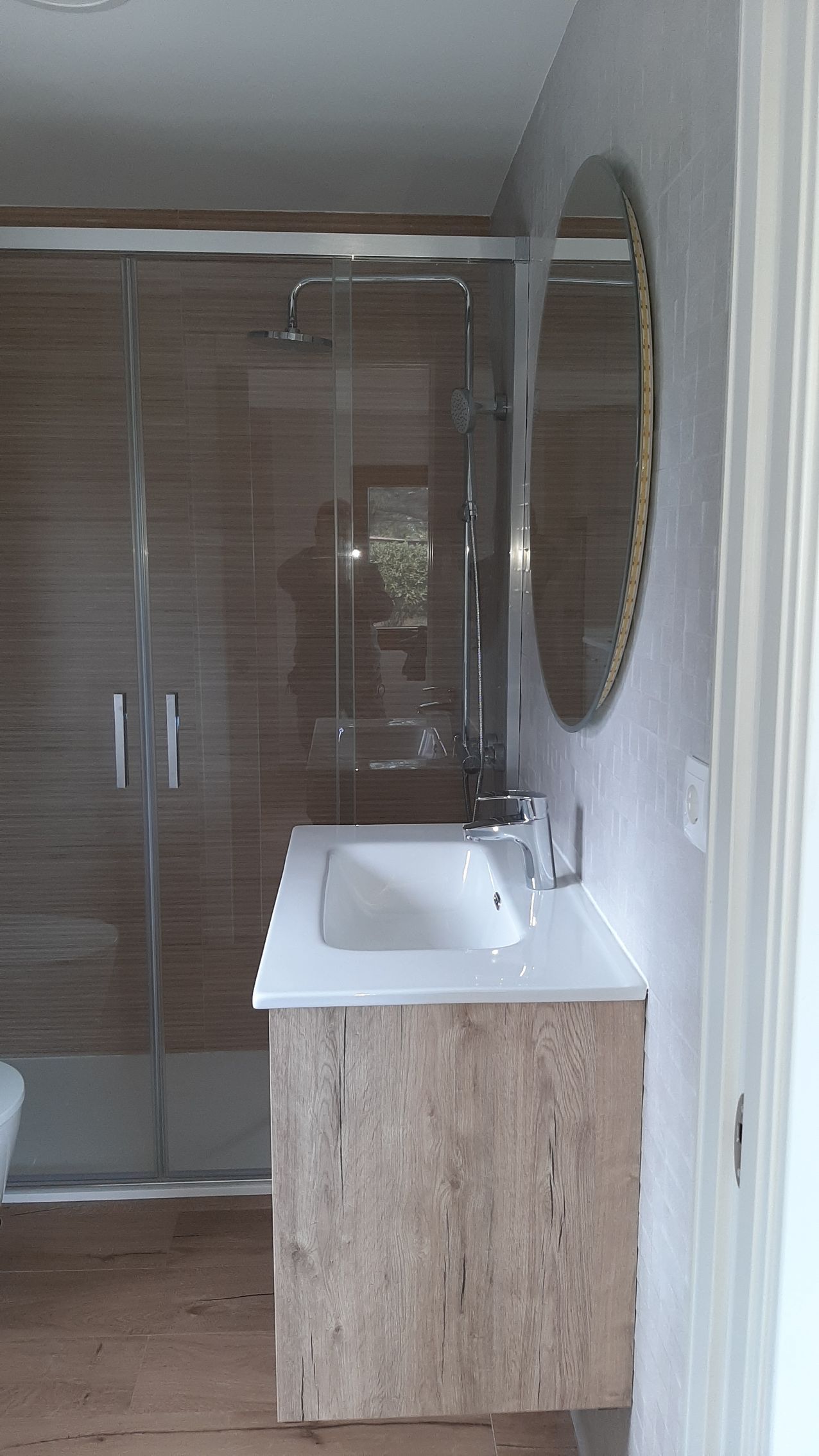 Un baño con lavabo, espejo y cabina de ducha.