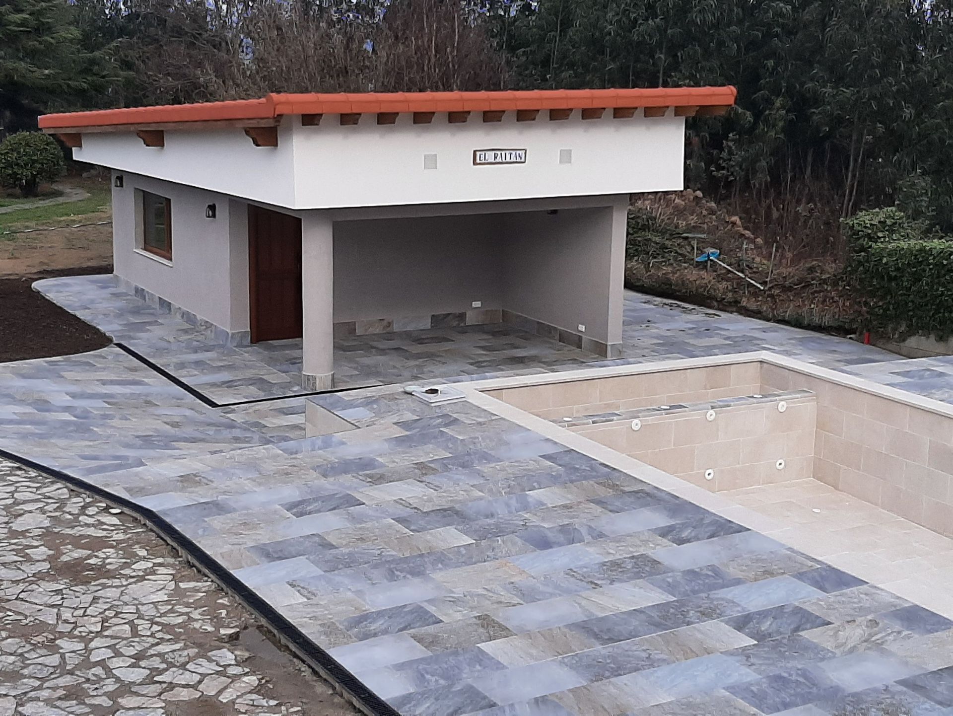 Un edificio blanco con techo rojo se encuentra junto a una piscina.