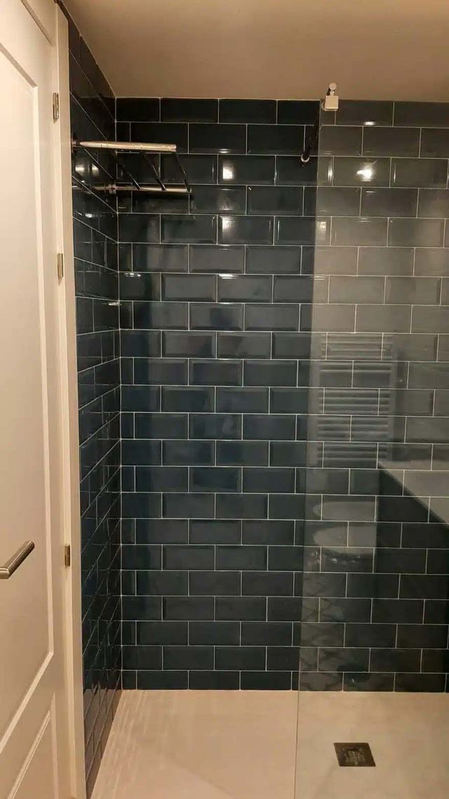 Un baño con azulejos azules y ducha a ras de suelo.