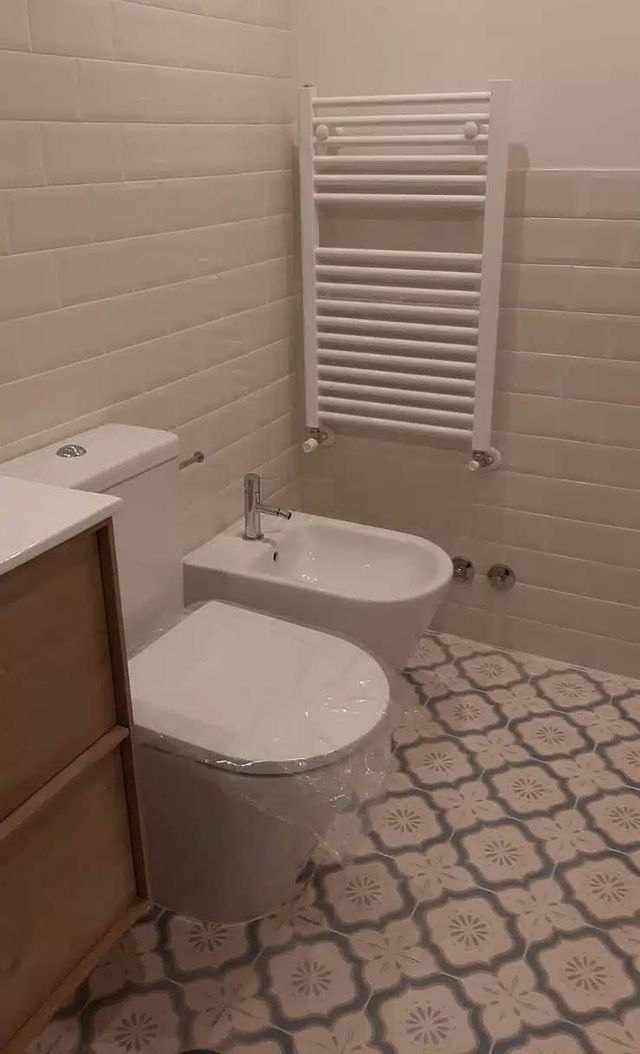 Un baño con inodoro, bidet y toallero.