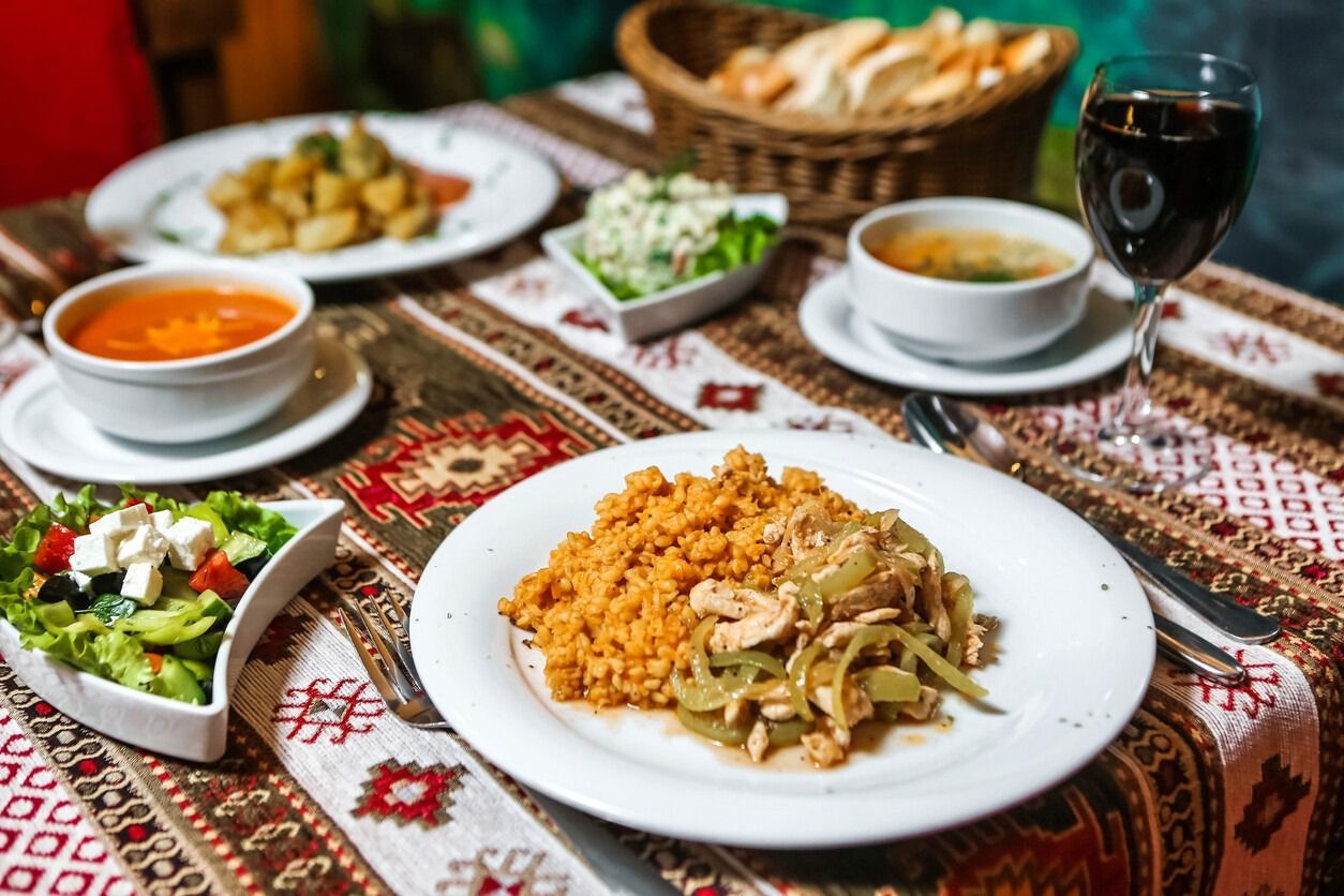 Una mesa cubierta con platos de comida y una copa de vino.