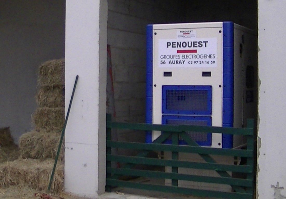 Générateur PENOUEST bleu et blanc dans une grange. Bottes de foin à gauche.