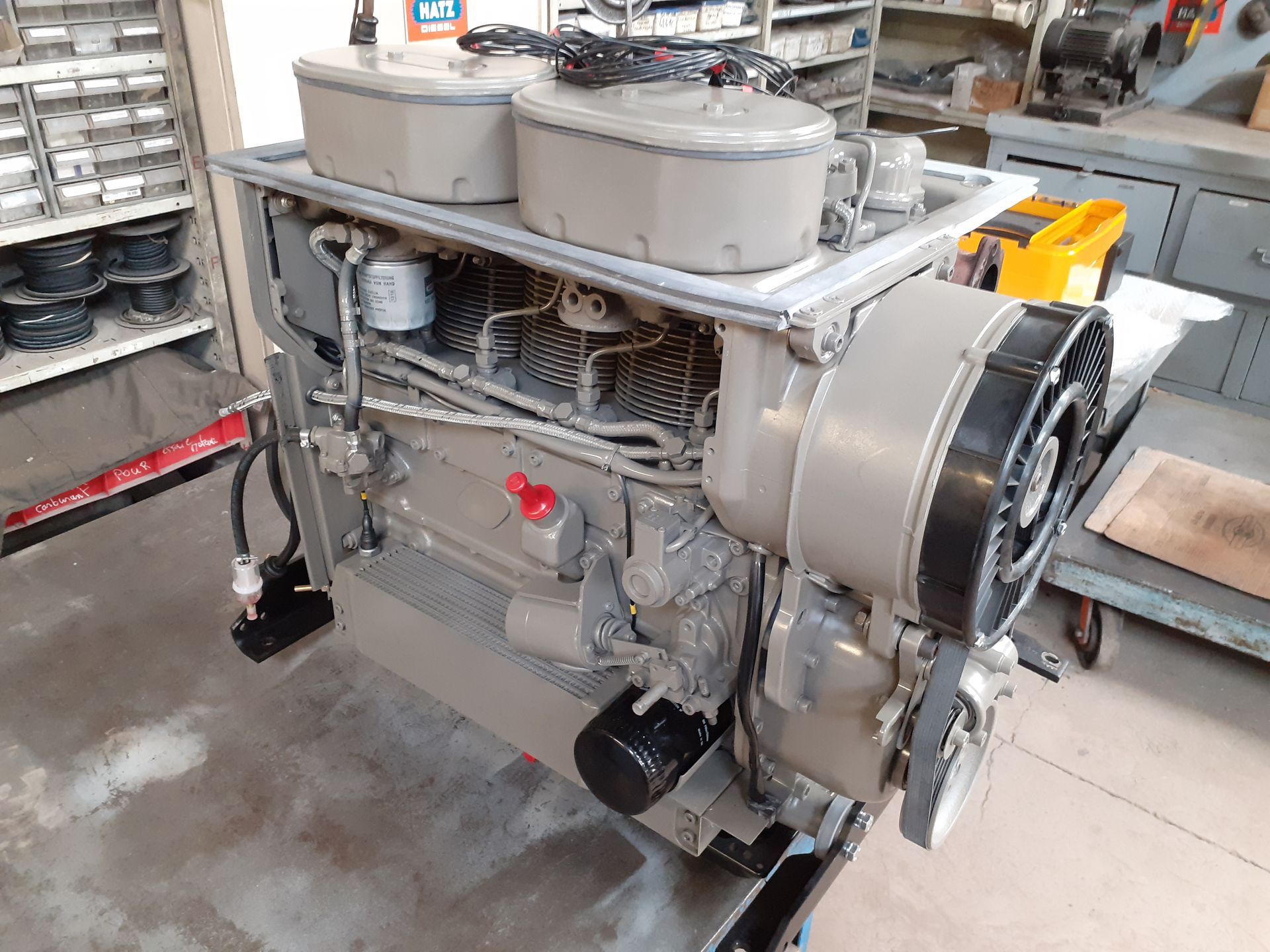 Moteur industriel avec filtres à air, tuyaux et ventilateur de refroidissement dans un atelier.