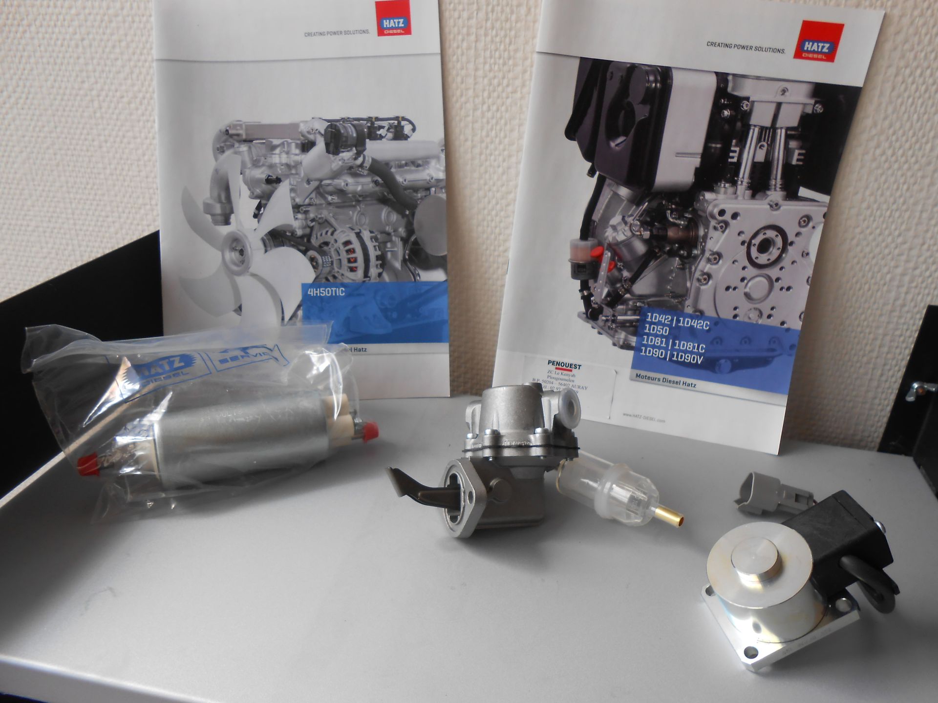 Pièces de moteur et brochures sur une table. Une pompe à carburant et d'autres composants.