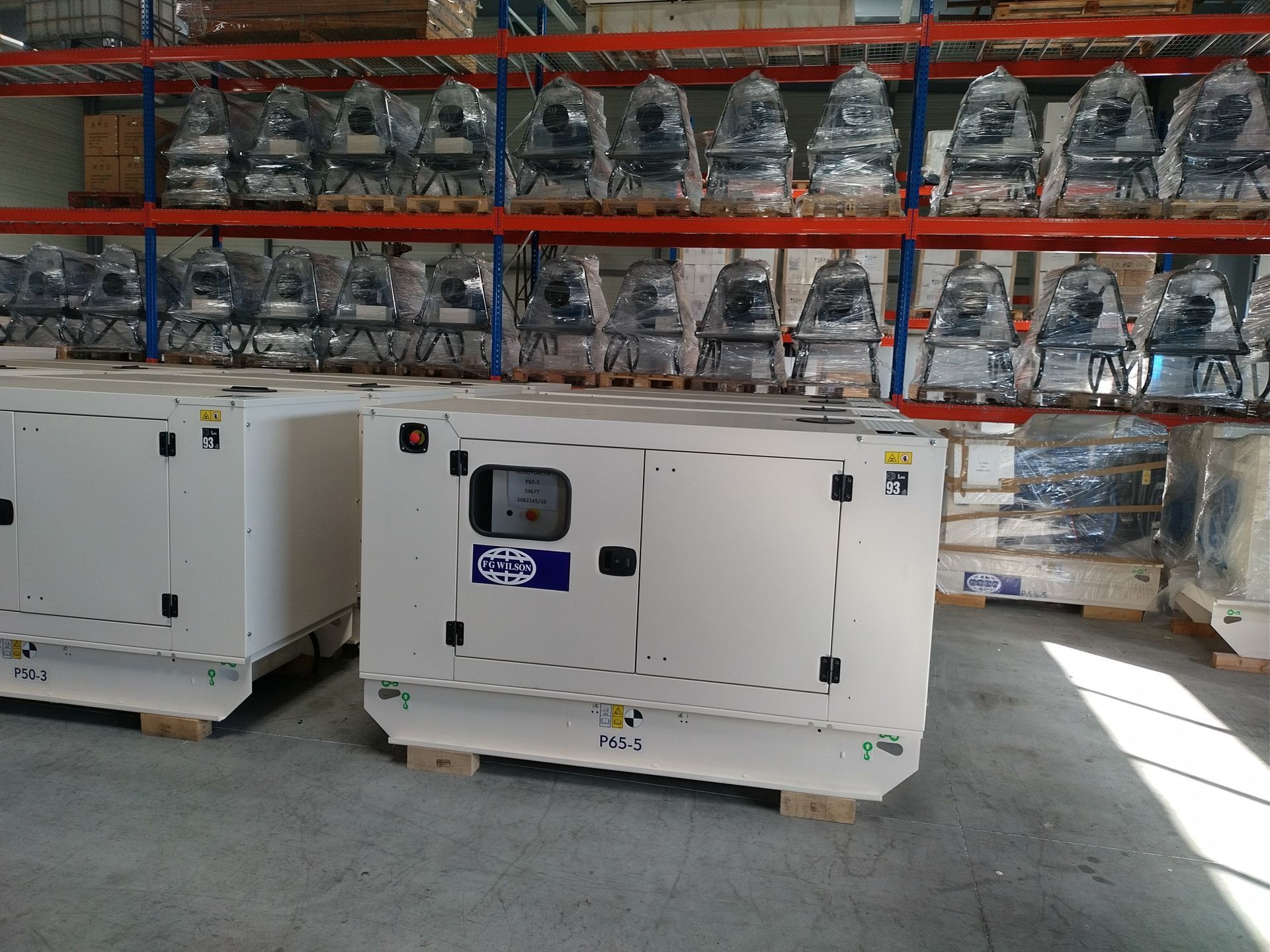 Deux générateurs blancs sur des palettes dans un entrepôt.