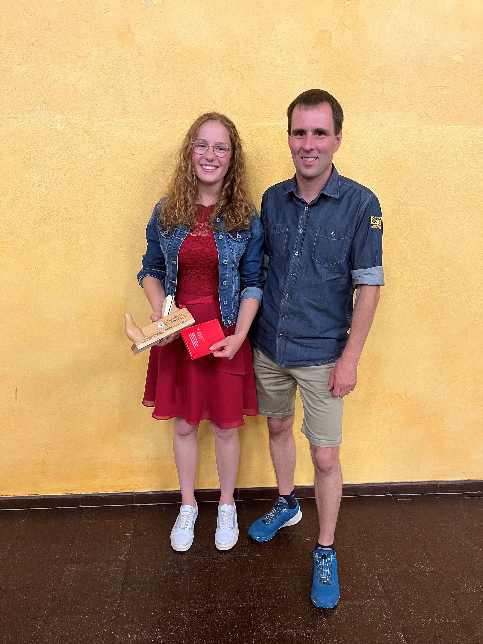 Ein Mann und eine Frau stehen nebeneinander vor einer gelben Wand.