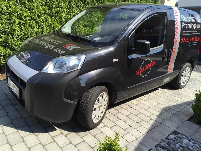 Ein schwarzer Lieferwagen steht auf einer gepflasterten Auffahrt