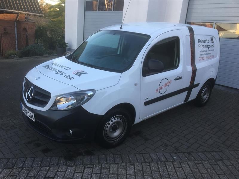 Ein weißer Lieferwagen steht vor einem Garagentor.