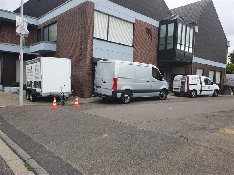 Drei weiße Lieferwagen stehen vor einem großen Gebäude