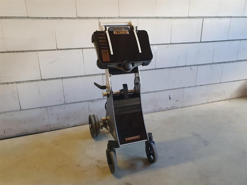 Ein schwarzer Trolley mit Rädern steht vor einer weißen Backsteinmauer