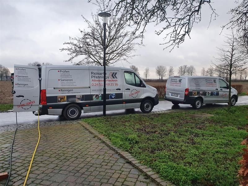 Zwei Lieferwagen stehen nebeneinander auf einem Gehweg.