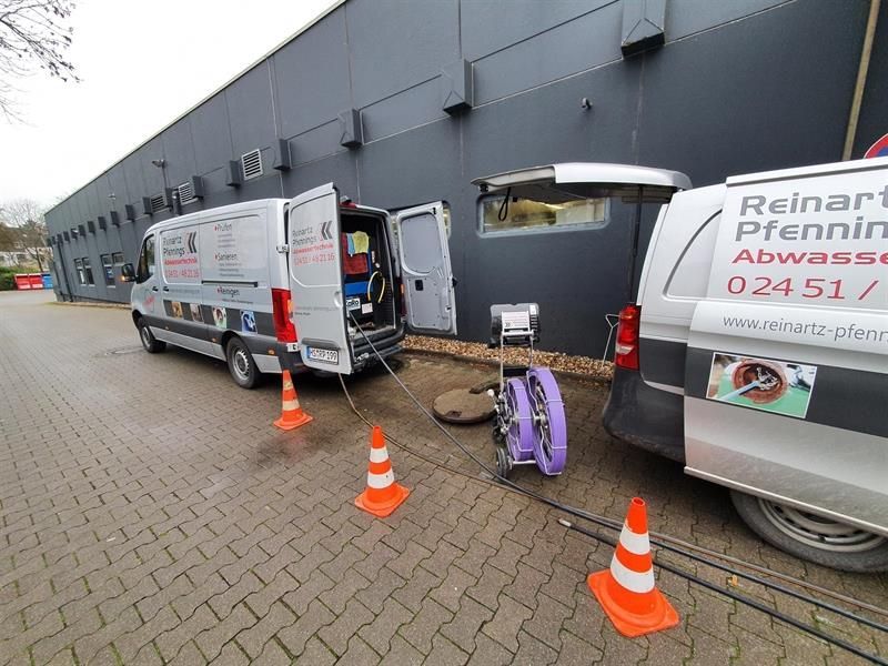 Vor einem Gebäude parken zwei Lieferwagen, einer davon trägt die Nummer 02451 auf der Rückseite