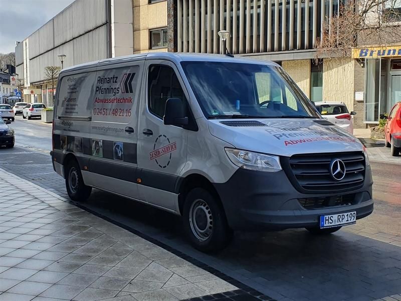 Ein Mercedes-Van steht am Straßenrand vor einem Gebäude.