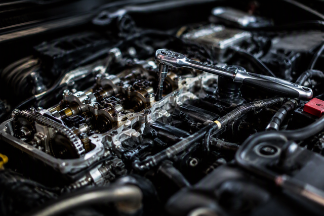 Fahrzeugprüfung und MFK‑Bereitstellung – alles aus einer Hand Nahaufnahme eines Automotors mit freiliegenden Metallteilen und einer obenauf liegenden Knarre