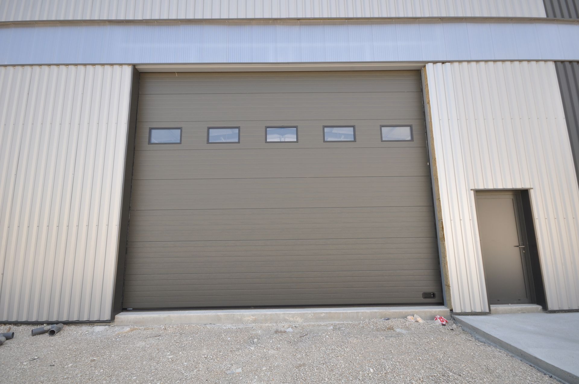 Porte de garage sectionnelle en alu avec de petites fenêtres.