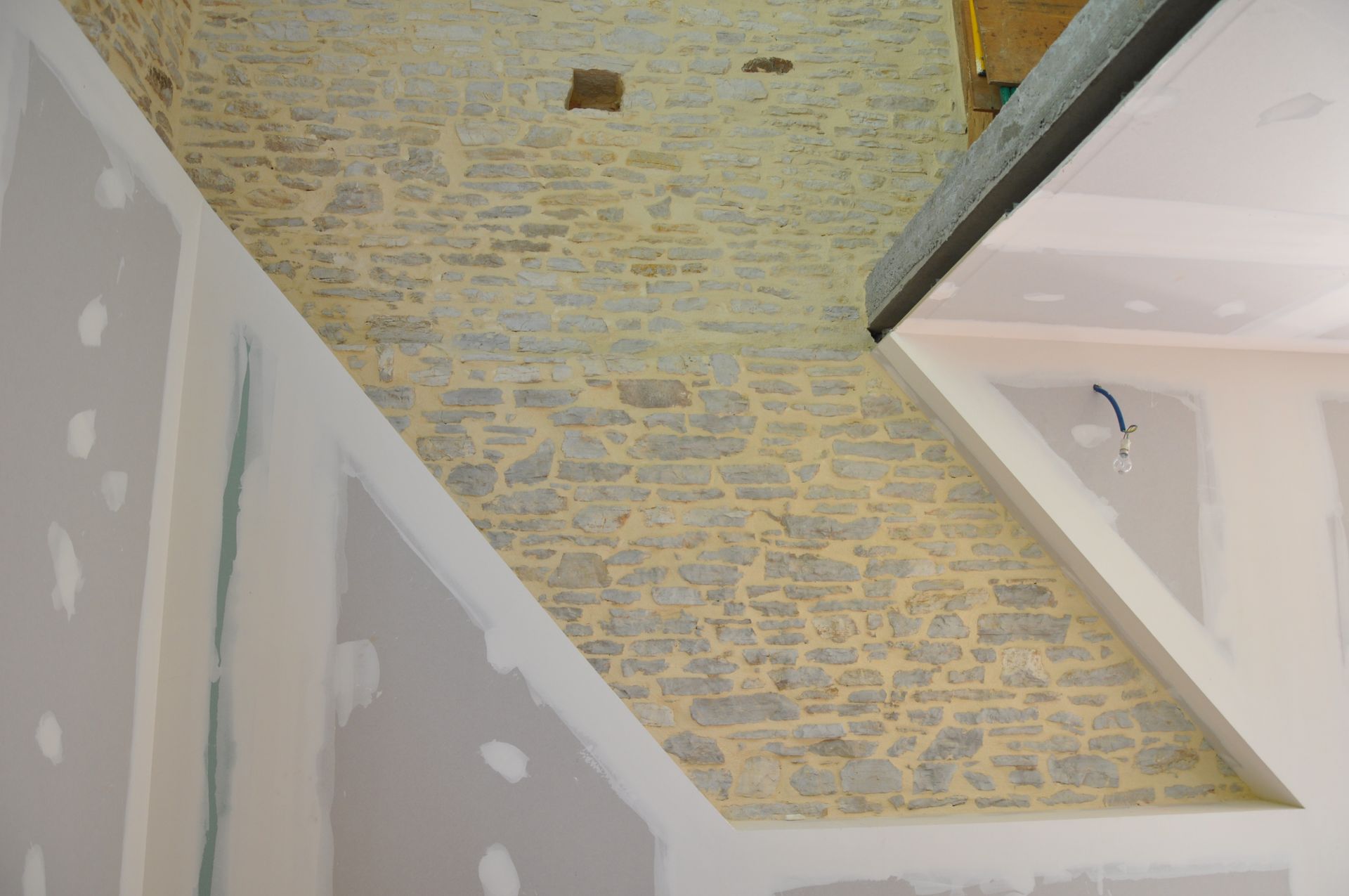 Isolation d'une partie d'un mur en plaques de plâtre, l'autre partie restant en pierres apparentes