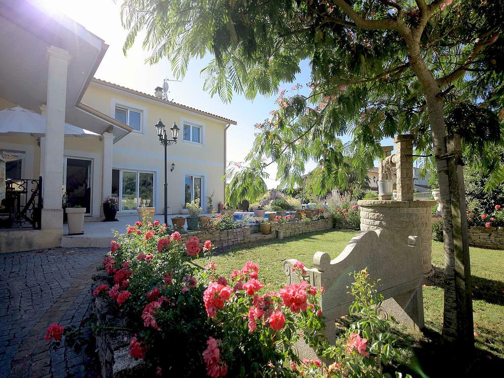 Jardin vert avec roses rouges, grand arbre et puit en pierre - réalisations