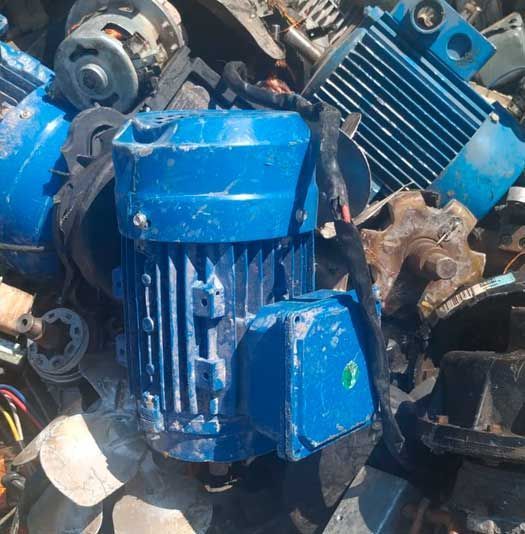 Un motor azul está parado en una pila de chatarra.