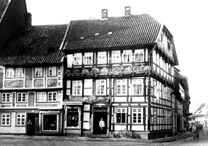 Historische Fachwerkhäuser an einer Straßenecke, mit Ladenfronten und Ziegeldach.