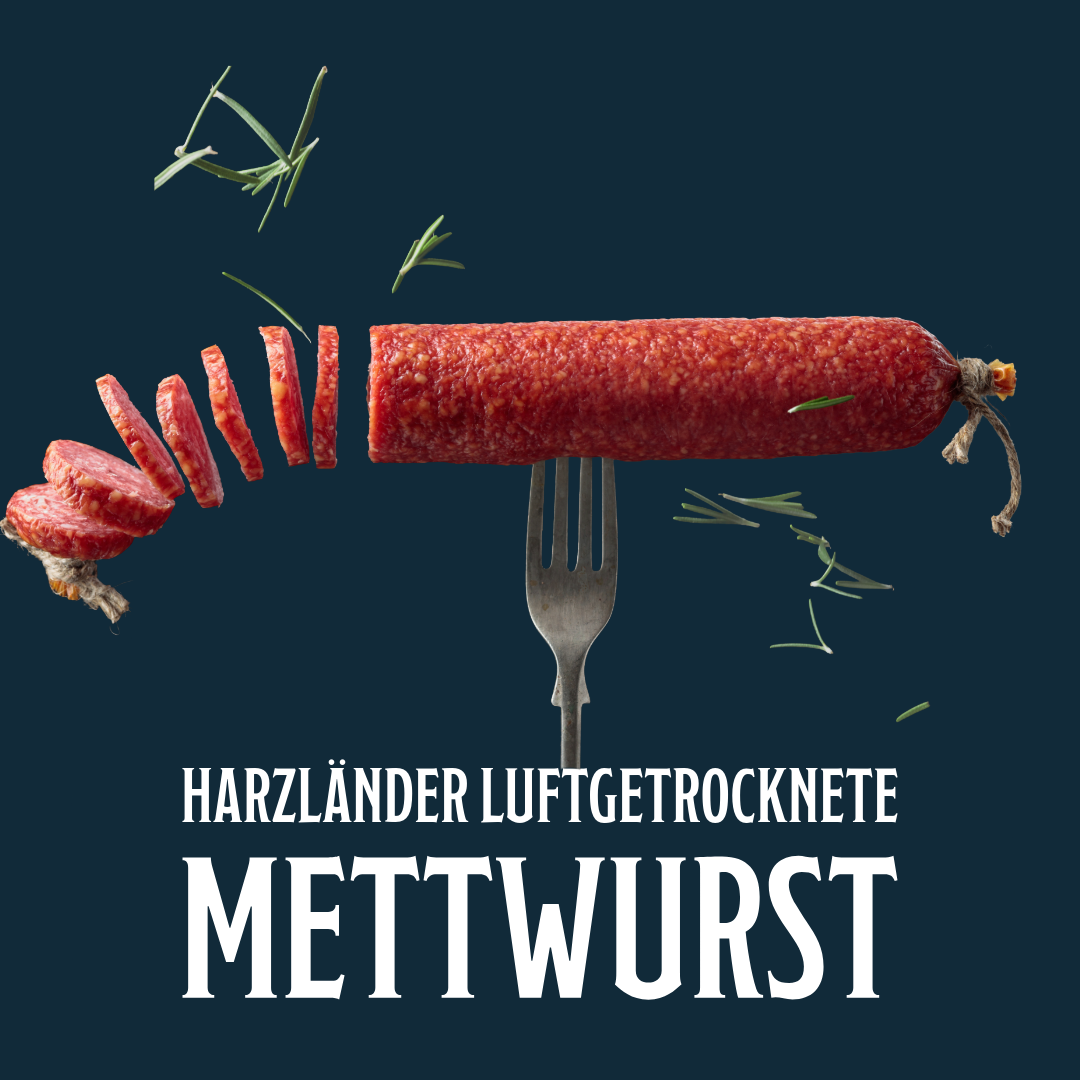 Harzländische Rohwurst, rot und in Scheiben geschnitten, auf dunkelblauem Hintergrund mit Gabel und Kräutern