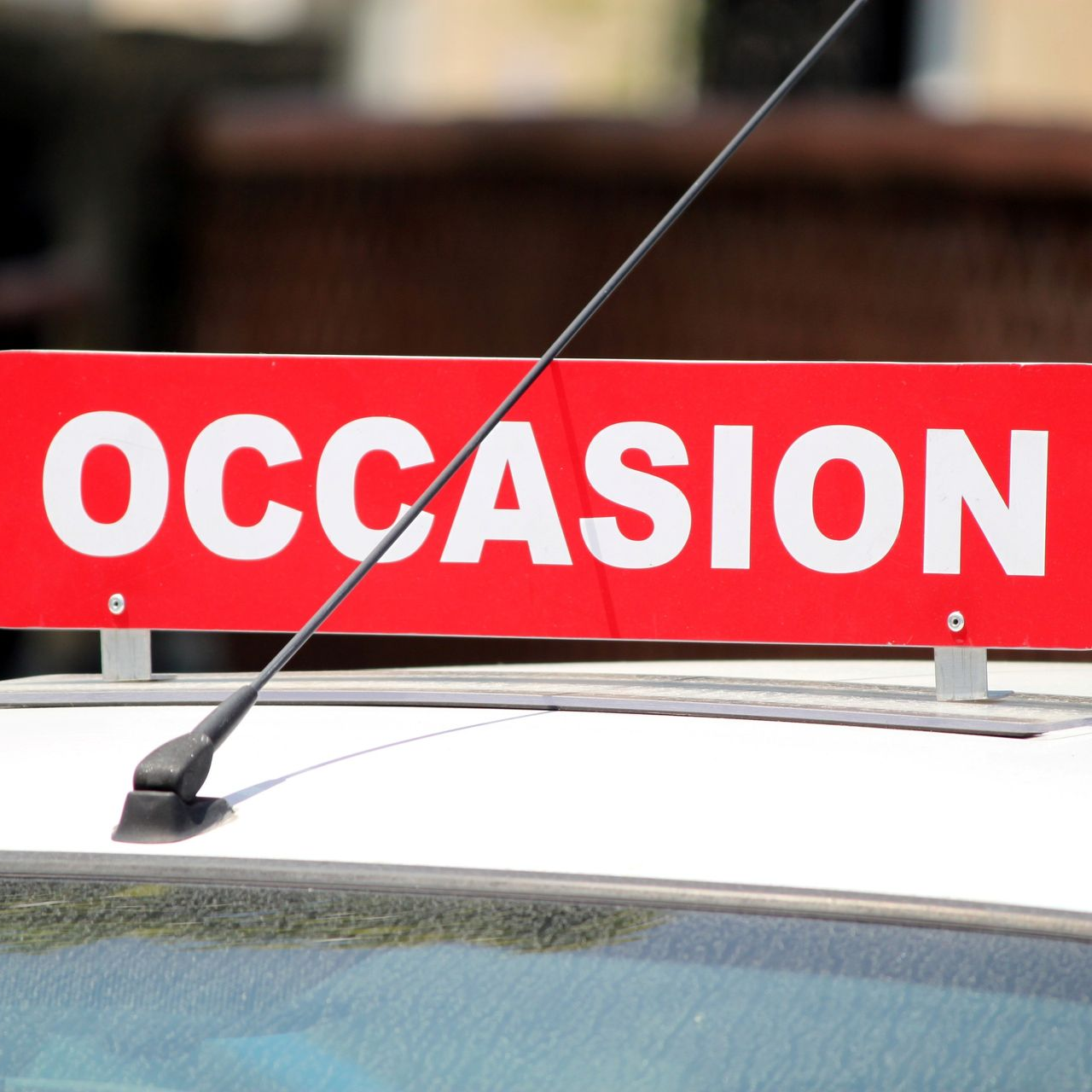 Des voitures alignées dans un hall d'exposition, avec une pancarte rouge SOLDES bien visible.