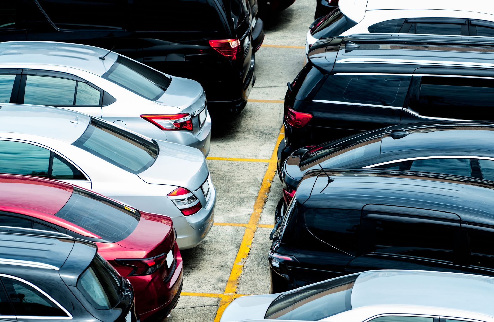 Voitures garées les unes contre les autres sur un parking extérieur ; couleurs variées visibles.