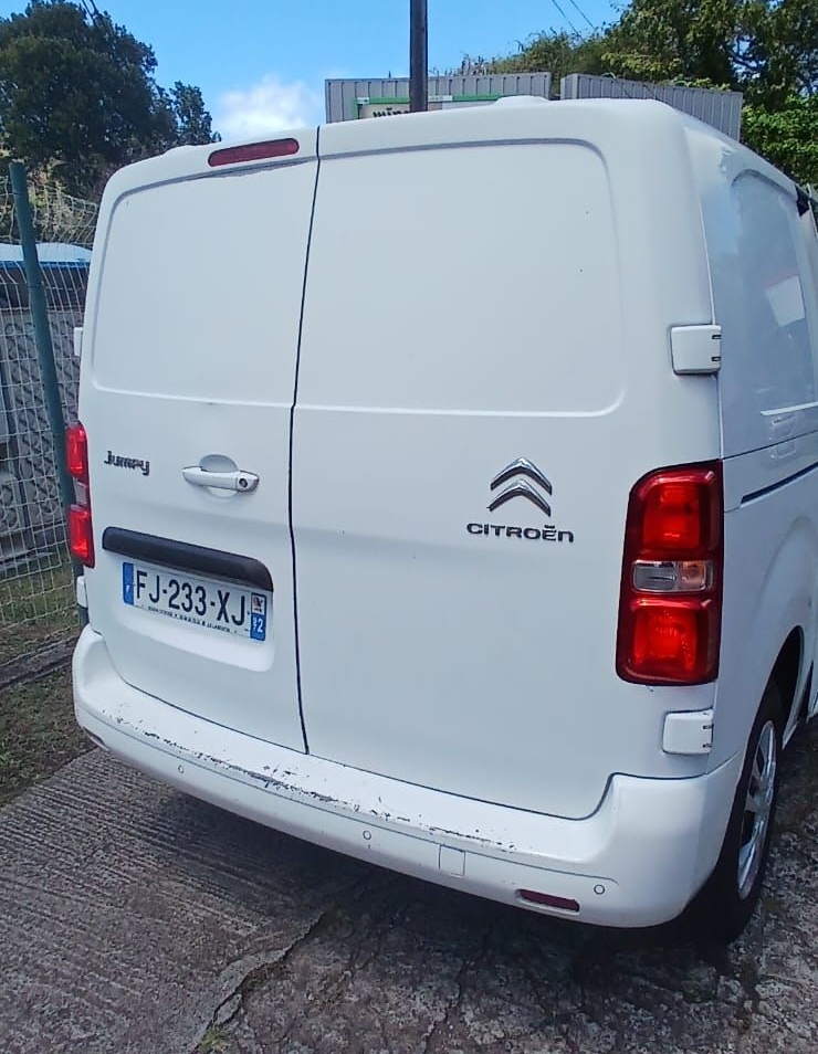 Une fourgonnette Citroën Jumpy blanche, garée à l'extérieur, vue de l'arrière avec une plaque d'immatriculation française.